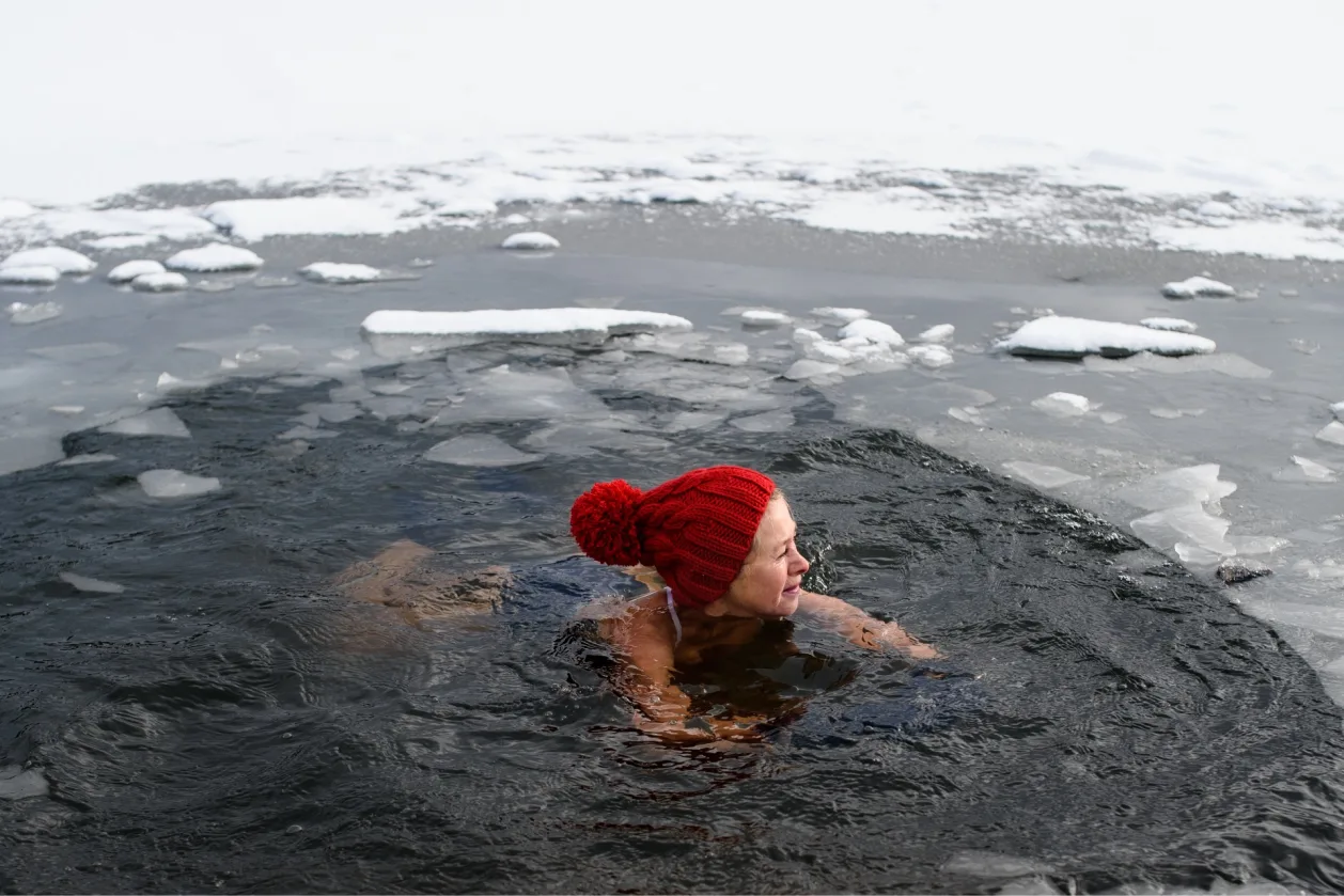 active-senior-woman-swimming-in-water-hole-in-frozen-lake-outdoors-in-winter-cold-therapy
